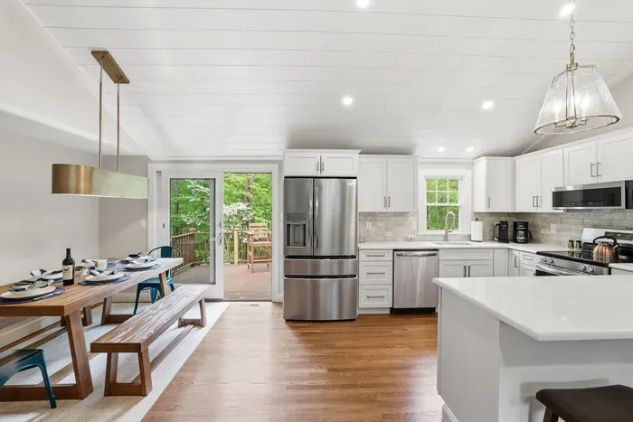 Bright modern kitchen with island, dining area, and deck access