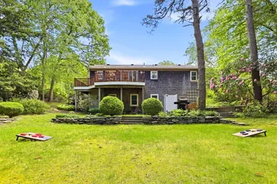 Spacious backyard with deck, grill, and lawn games under the trees