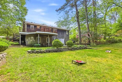 Spacious backyard with wraparound deck, wooded privacy, and lawn games