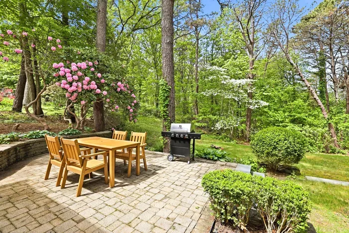 Private garden patio with outdoor dining, grill, and peaceful wooded views