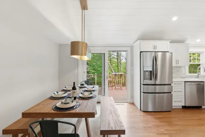 Bright modern kitchen and dining area with deck access and forest views