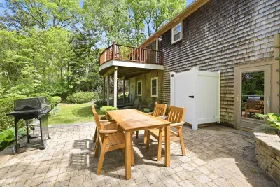 Private patio with grill, dining set, and peaceful tree-lined backyard