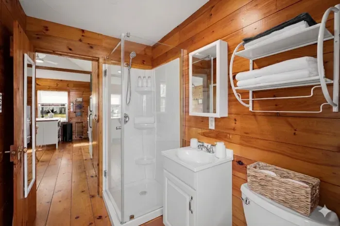 Rustic wood-paneled bath with glass shower and bright modern touches