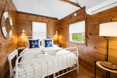 Relax in this cozy room featuring a queen-size bed, complete with charming decorative ship cushions for a touch of coastal flair