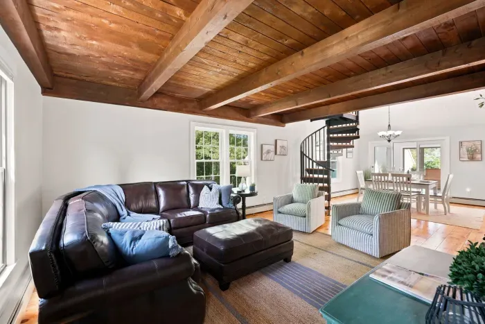 Cozy open living space with exposed beams, natural light, and dining area