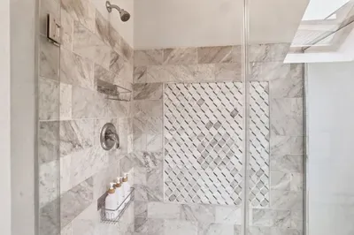 Spa-like marble shower with glass enclosure and natural skylight