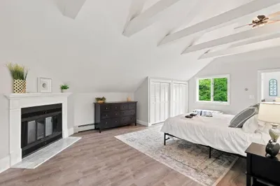 Spacious vaulted bedroom with fireplace and serene natural light