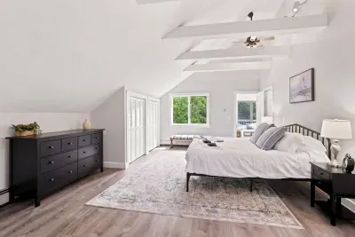 Bright vaulted bedroom with exposed beams and peaceful garden views