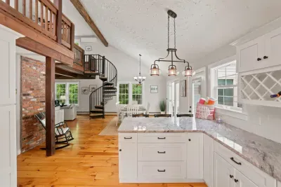 Bright open kitchen with vaulted ceilings, spiral staircase, and rustic charm