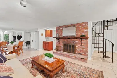 Bright open living area with brick fireplace and charming spiral staircase
