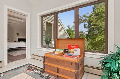 Sunny reading nook with big windows, leafy views, and guest-friendly games