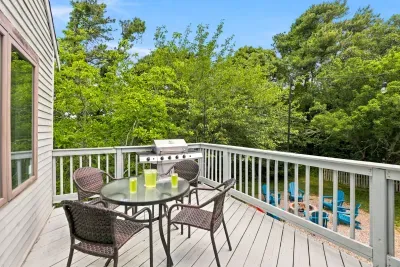 Private tree-lined deck with grill, dining table, and fire pit below