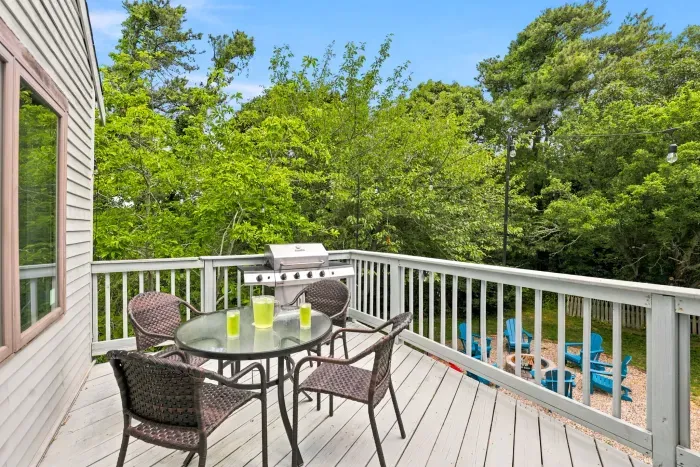Private tree-lined deck with grill, dining table, and fire pit below