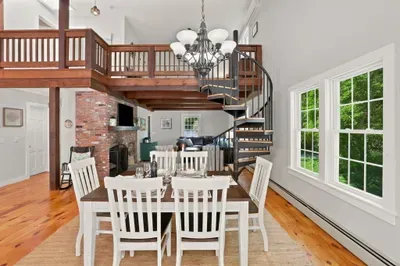 Bright loft-style dining area with spiral staircase and brick fireplace