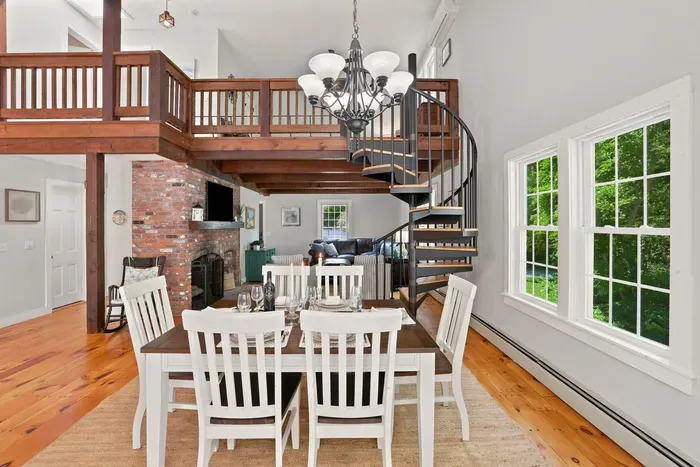 Bright loft-style dining area with spiral staircase and brick fireplace