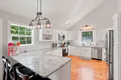 Bright gourmet kitchen with granite island, vaulted ceilings & bar seating