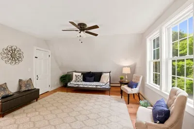 Sunny sitting room with large windows, cozy seating, and peaceful views