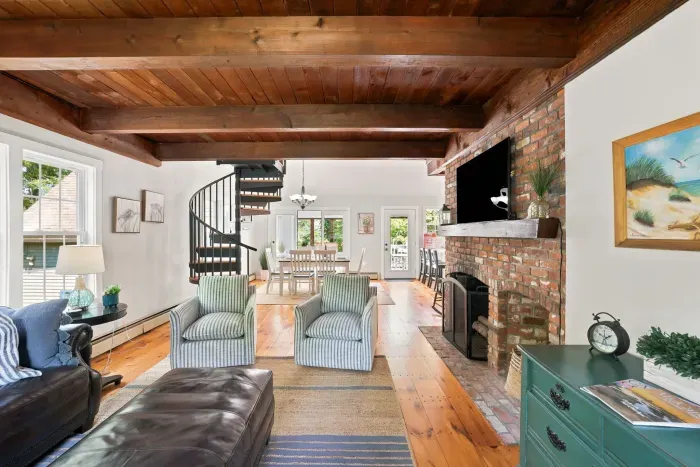 Cozy living room with brick fireplace, wood beams & charming spiral staircase