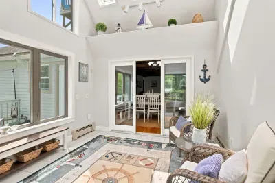 Sun-filled coastal sunroom with wicker seating and dining access