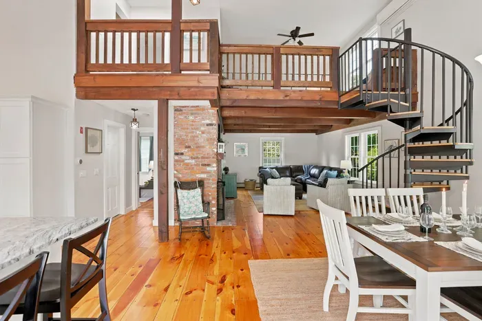 Open-concept great room with loft, spiral staircase, and warm wood floors