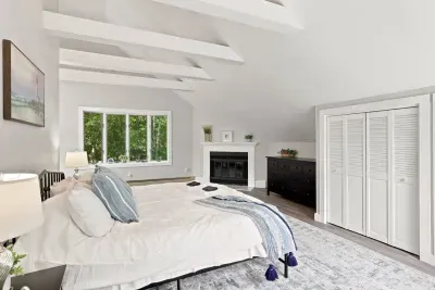 Bright vaulted bedroom with fireplace, large window, and serene style