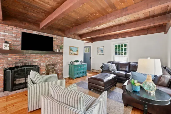 Cozy rustic living room with brick fireplace, TV, and exposed wood beams