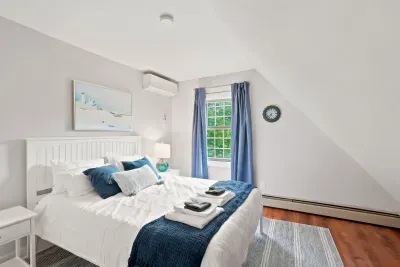 Cozy, sunlit bedroom with plush bedding, hardwood floors, and AC