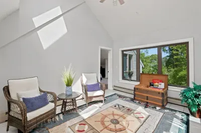 Sunlit loft-style lounge with vaulted ceilings and serene wooded views