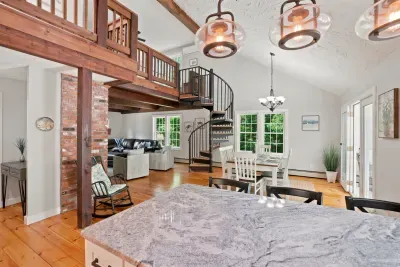 Bright open-concept great room with loft, spiral stairs, and sunny dining area
