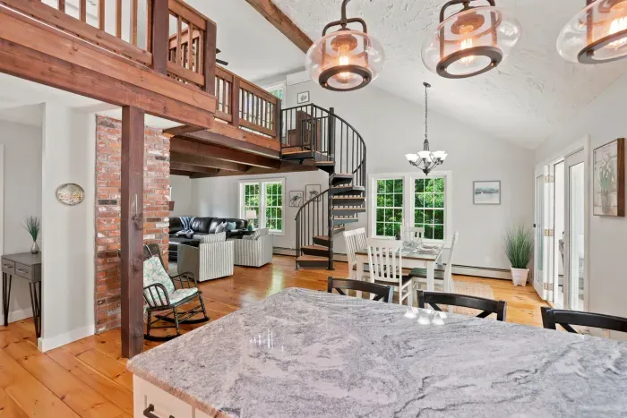 Bright open-concept great room with loft, spiral stairs, and sunny dining area