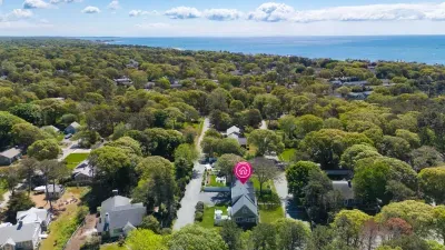 Aerial view of a peaceful coastal home surrounded by trees near the beach