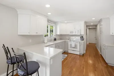 Bright white kitchen with breakfast bar, ample counter space, and hardwood floors