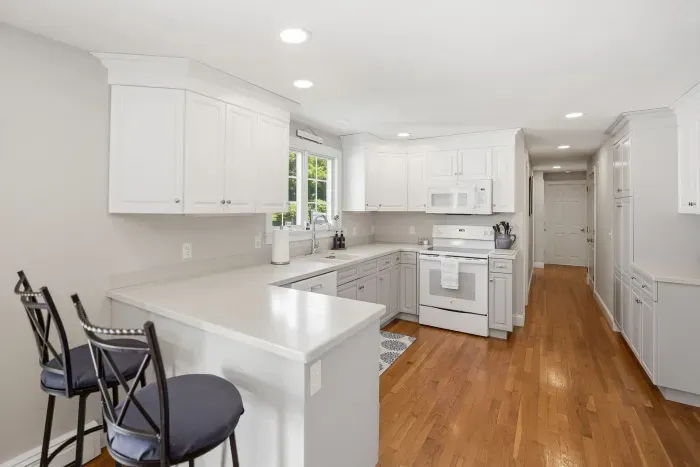 Bright white kitchen with breakfast bar, ample counter space, and hardwood floors