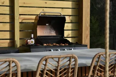 Enjoy a backyard BBQ with our propane grill and Blackstone grill conveniently under the cover of the backyard pergola.