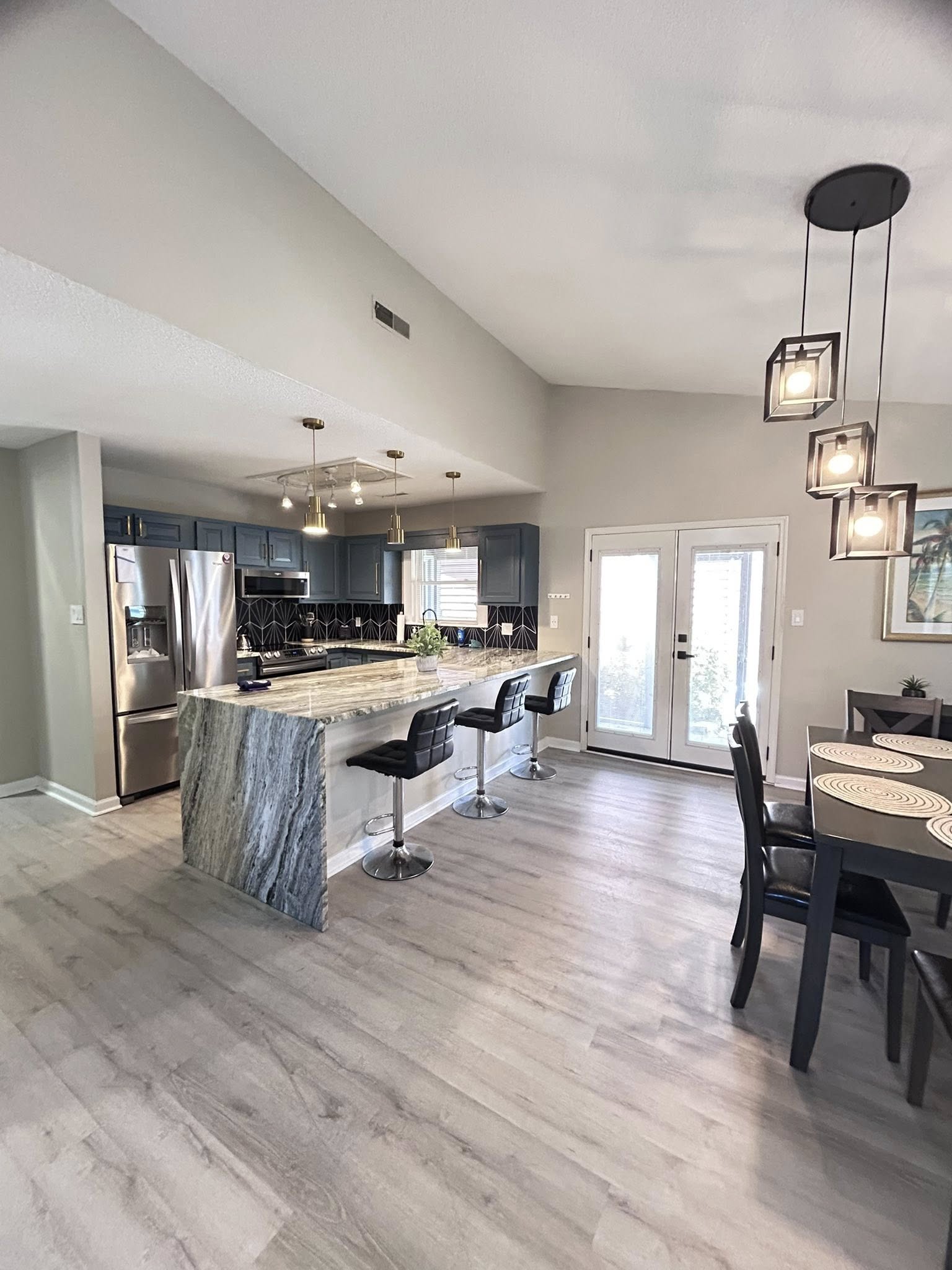 Modern open kitchen with waterfall island, bar seating, and bright dining area