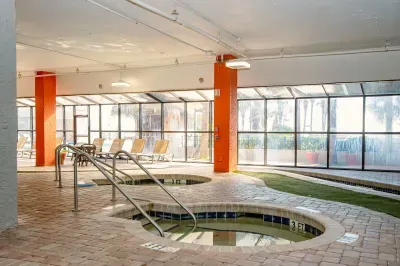 Sunny indoor pool area with hot tubs and lounge seating
