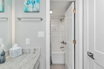 Bright coastal bathroom with marble vanity and modern tiled tub-shower