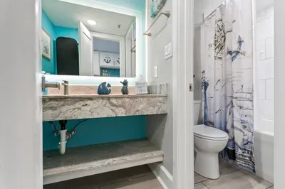 Bright coastal bath with backlit mirror and stylish marble-look vanity