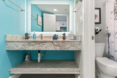 Bright coastal bathroom with marble vanity and illuminated mirror