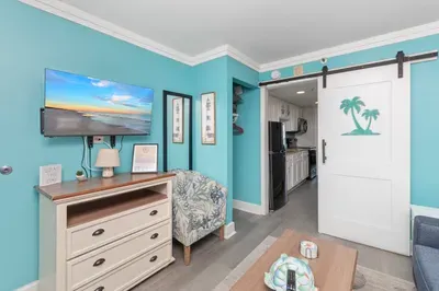 Coastal-chic living area with TV, barn door, and easy kitchen access