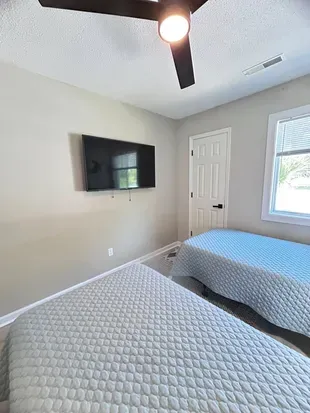 Bright twin bedroom with wall-mounted TV and natural light
