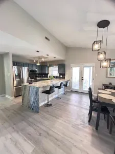 Modern open kitchen with waterfall island, bar seating, and bright dining area