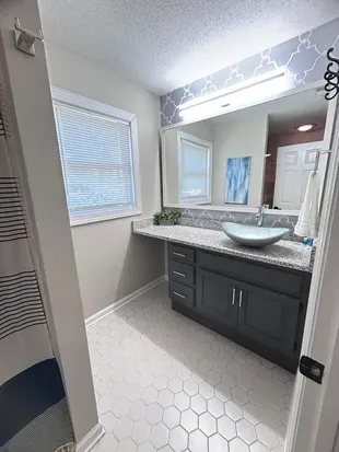 Bright modern bathroom with vessel sink, granite vanity, and stylish finishes