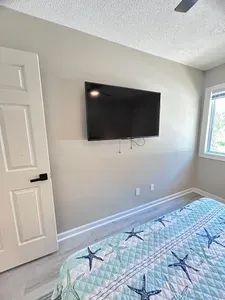 Bright coastal-style bedroom with wall-mounted TV and natural light
