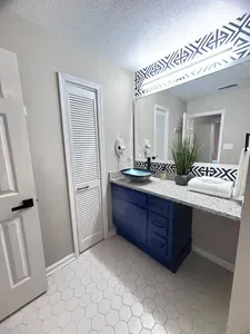 Modern bathroom with bold blue vanity, granite counter, and stylish accents