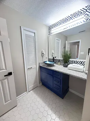 Modern bathroom with bold blue vanity, granite counter, and stylish accents