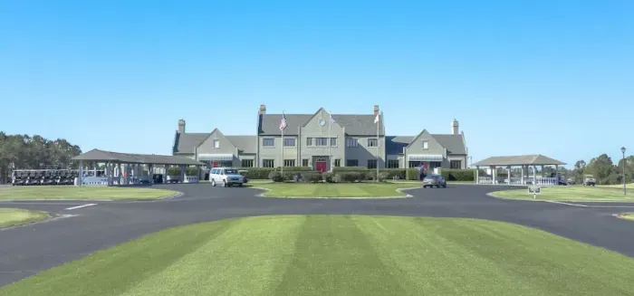 Elegant golf clubhouse with carts, dining, and easy tee-time access by manicured greens.