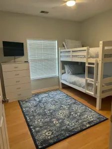 Cozy bunk room with TV, storage & stylish rug—perfect for kids