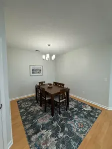 Bright dining nook with 6‑seat table, statement rug, and modern chandelier.