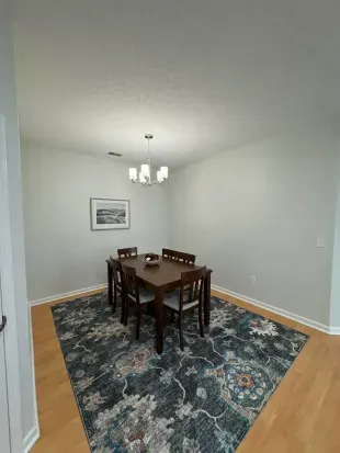 Bright dining nook with 6‑seat table, statement rug, and modern chandelier.